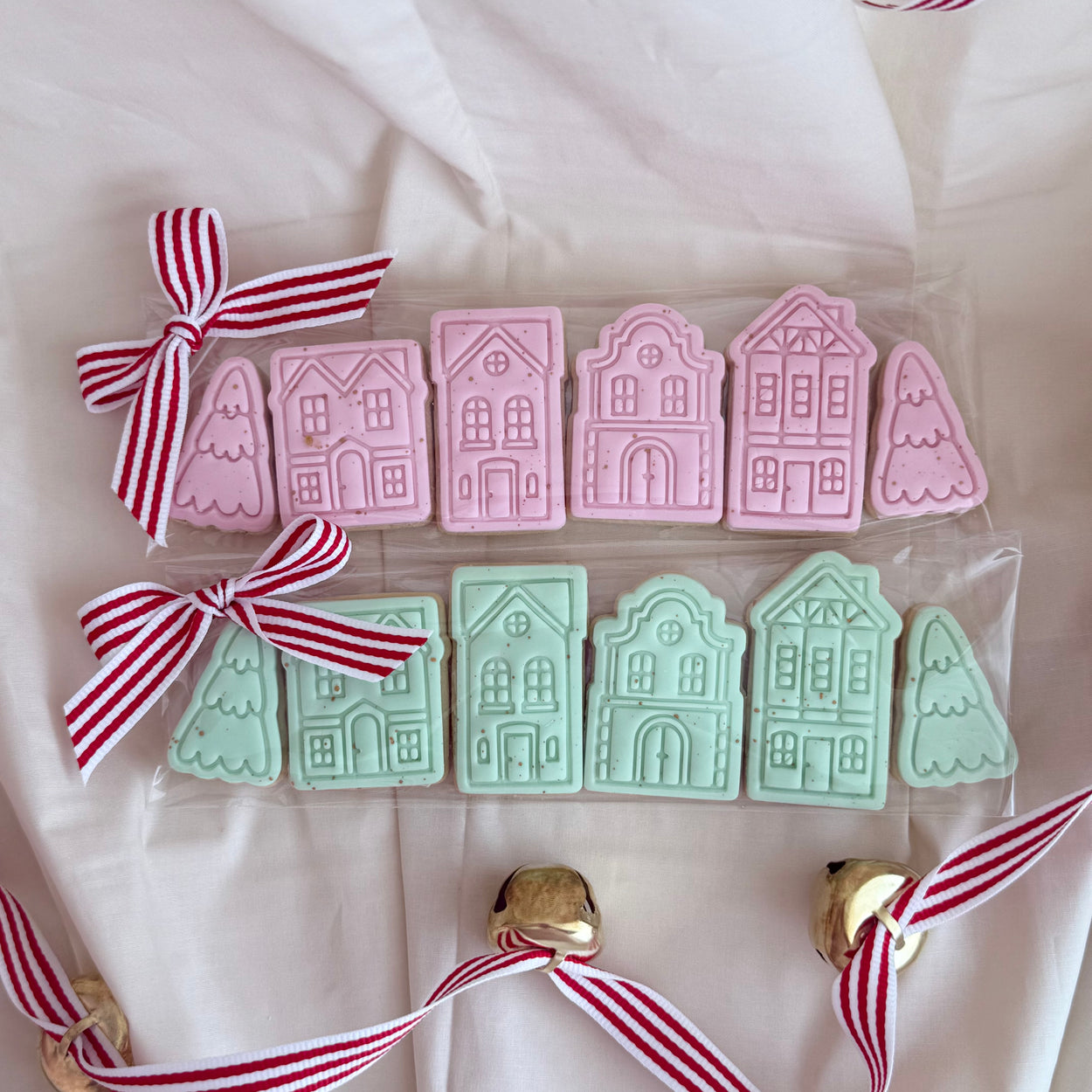 Set of hand-decorated mini Christmas cookies shaped like a festive holiday village, including snow-capped houses and seasonal decorations, perfect for gifting or holiday celebrations.