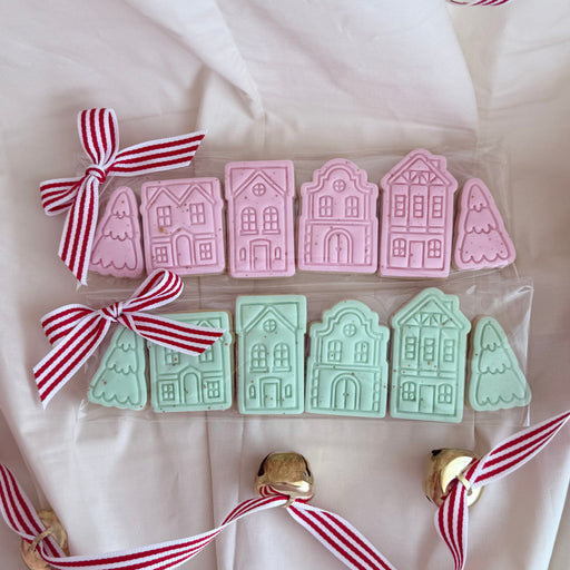 Set of hand-decorated mini Christmas cookies shaped like a festive holiday village, including snow-capped houses and seasonal decorations, perfect for gifting or holiday celebrations.