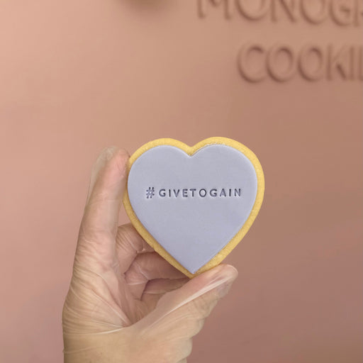 Heart-shaped cookie with 'givetogain' text for International Women's Day 2026